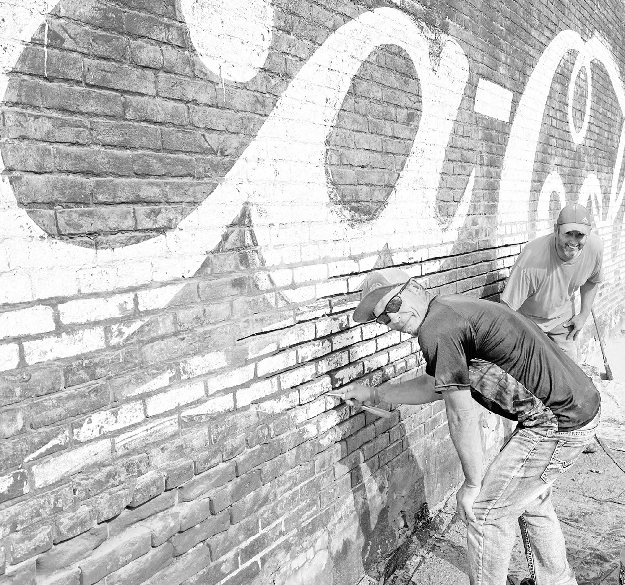 RESTORING THE PAST: Shaun Kern, foreground, and Dustin Burnett are assisting 231 W. Main St. building owner Mike Gentry with preservation/restoration of the building’s west external wall. Gentry is considering multiple options for the building but he said his first step was preservation.