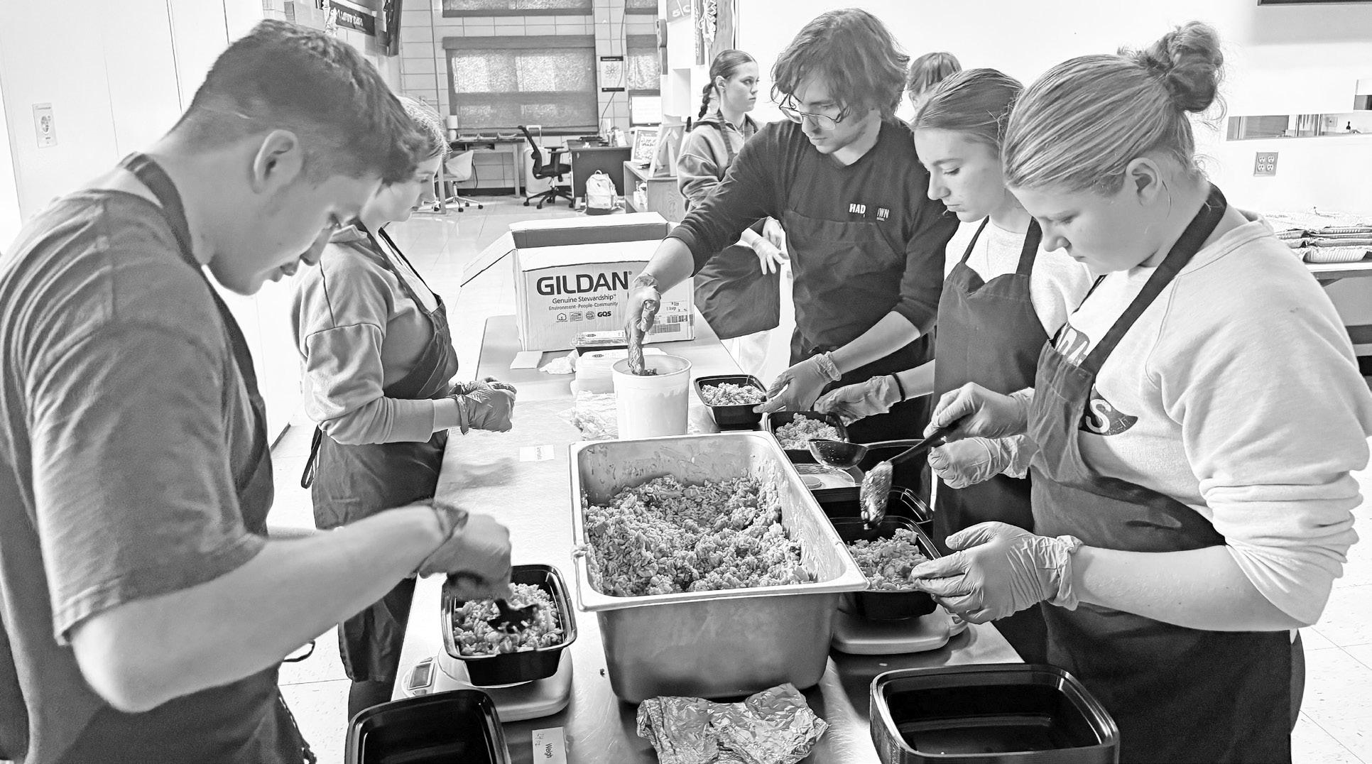 PACKAGING chicken fried rice for distribution in the Kids Feeding Kids project. Pictured left to right are - Mason Wilkens, Maya Mulryan, Mia McCormick (in background), Mr. Meals, Milo Nelson and Morgan Romme.