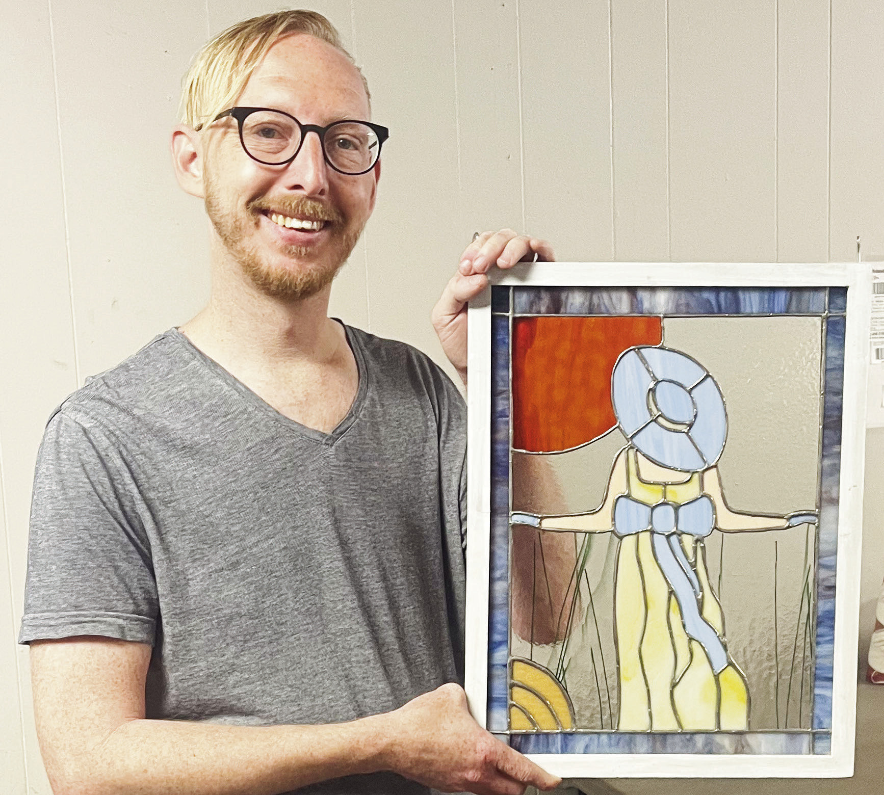 Adam Koci of Emporia holds “Prairie Stroll,” one of seven stained glass pieces now on display in the Council Grove Republican windows through Street Gallery KS, a division of the Bowers Center.