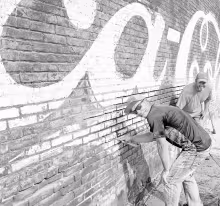 RESTORING THE PAST: Shaun Kern, foreground, and Dustin Burnett are assisting 231 W. Main St. building owner Mike Gentry with preservation/restoration of the building’s west external wall. Gentry is considering multiple options for the building but he said his first step was preservation.