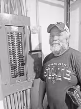Tom Van Valkenburg, Director of Facilities at USD 417, stands beside an electrical panel in the 1960s addition of the school where every breaker slot is full, with no room for expansion.