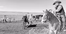 Working the ranch: in the “Oasis on the Prairie” Documentary, Cade Burden can be seen as the calf roper. Three generations of Perriers are behind him with Grandpa Tom at the table in the distance, his son Matt and his kids Hannah and Henry near the ca
