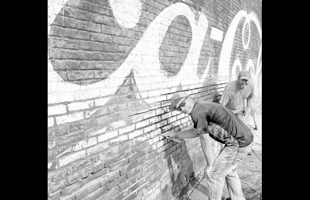 RESTORING THE PAST: Shaun Kern, foreground, and Dustin Burnett are assisting 231 W. Main St. building owner Mike Gentry with preservation/restoration of the building’s west external wall. Gentry is considering multiple options for the building but he sa