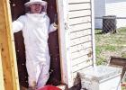 Suited up for protection is Callahan McIver. Callahan and Melinda McIver talked for a year about getting into bees “someday.” They took a course in Manhattan together in June of 2020. Two weeks later friends told the McIvers that they had a swarm in a Through Your Eyes